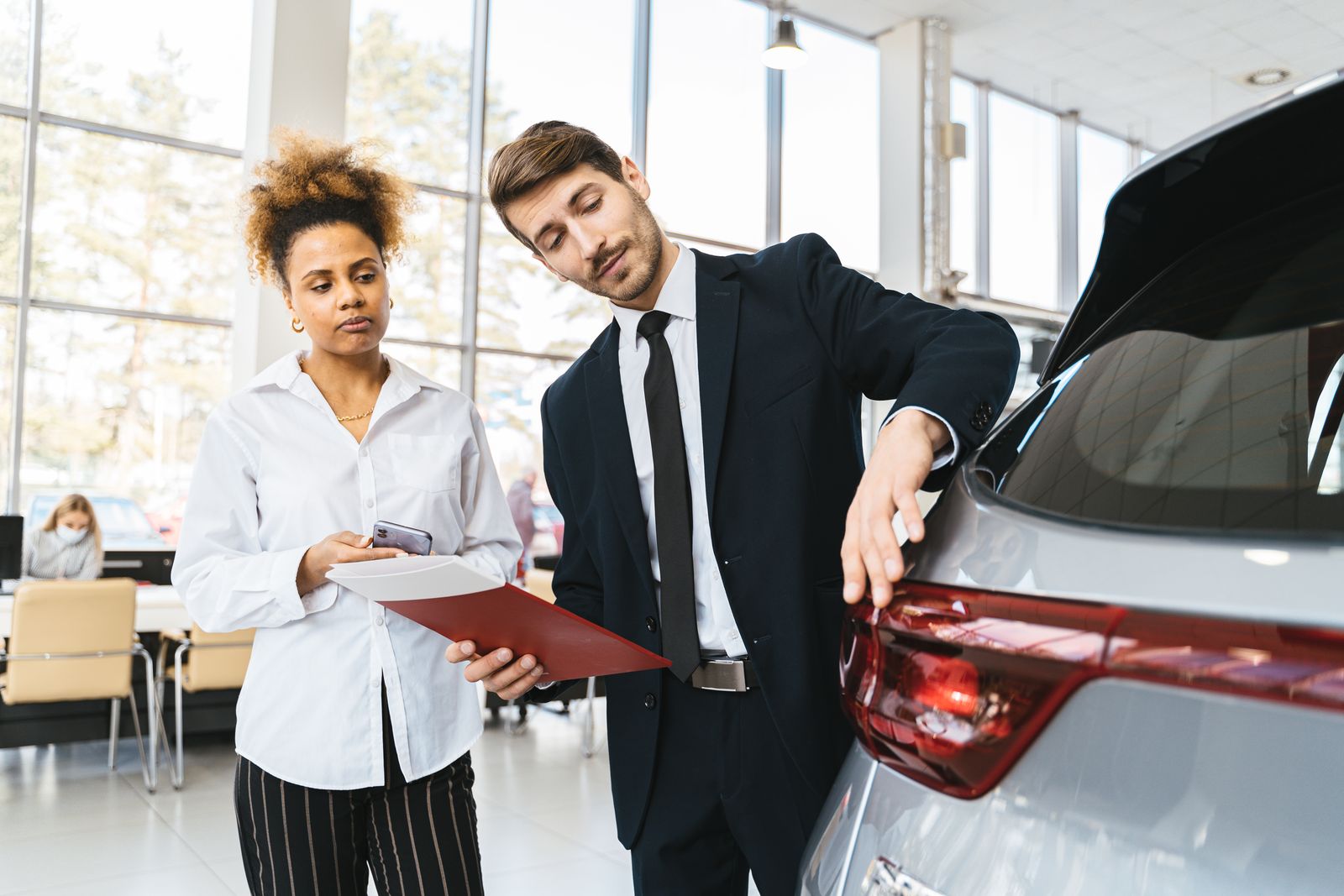 Customer and salesperson looking over a car at a dealership