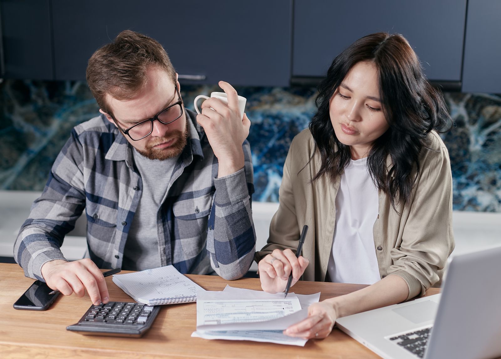 Couple reviewing bills and a budget at home with a calculator